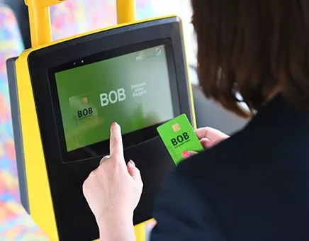 Eine Person mit BOB-Karte in der Hand am Automaten.