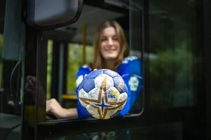 Frau mit Handball am Busfenster